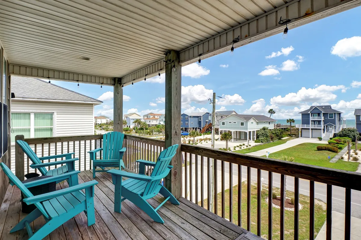 An inviting wooden deck furnished with turquoise chairs overlooks a scenic landscape, ideal for group gatherings or relaxing with a view. The image conveys the atmosphere of outdoor lunches or quiet moments with family, tying in with the mention of sound-side decks for group meals.