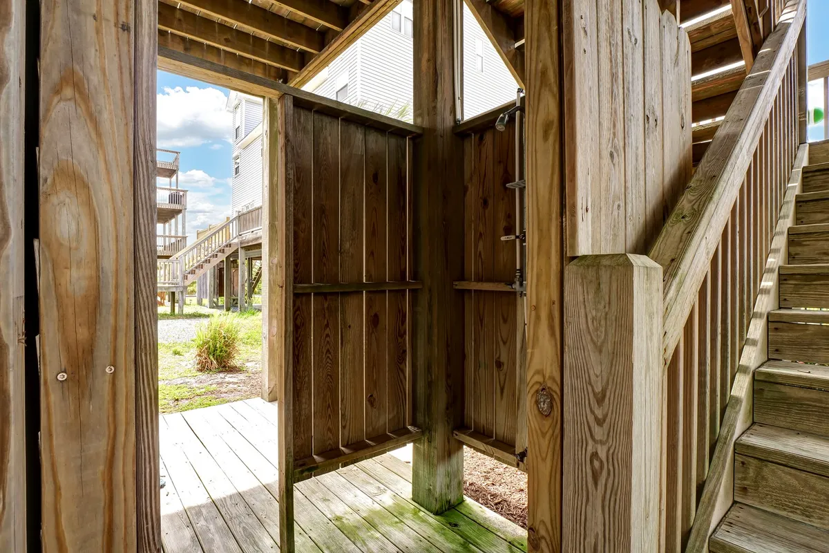 An inviting interior scene of a wooden staircase, open doorway, and textured wooden walls—suggesting easy-to-clean, practical surfaces and a transition area for returning from outdoor activities like the beach.
